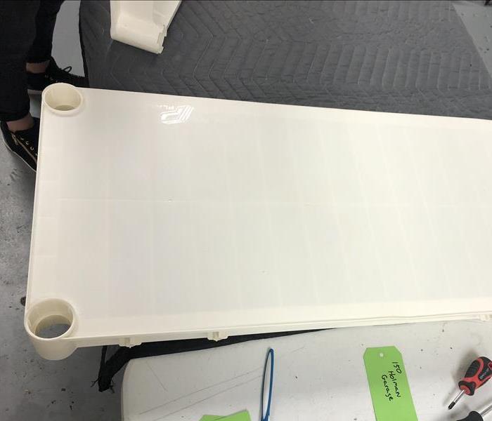 White plastic shelf sitting on a table after cleaning