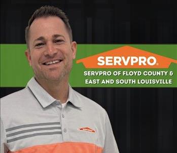 man smiling and staring at camera with a black background and a SERVPRO logo